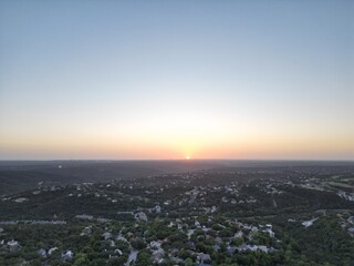Fototapeta premium Sunset over the city and hill country. Clear blue skies. Orange sun. Vistas and panoramas.