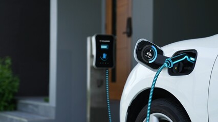 EV charger from home charging station plugged in and recharging electric car displaying digital...