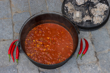 Top view of chili con carne cooked in the dutch oven with red hot peppers. 