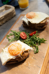 
Croque Madame Sandwich: A Traditional Breakfast of French Toast with Cheese and Fried Egg, Served on a Wooden Tray.