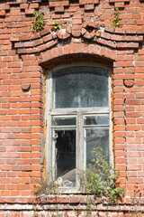 Fototapeta na wymiar Window of an old red brick building in the village of Stolptsy, Ryazan region. Building near the ruins of a former needle factory built in 1718