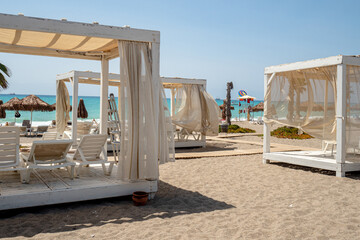 typical tropical atmosphere, beach holiday relax during sunny day in coastal resort with palm trees, baldaquin, deckchairs and ocean in the back, nobody © jan_S