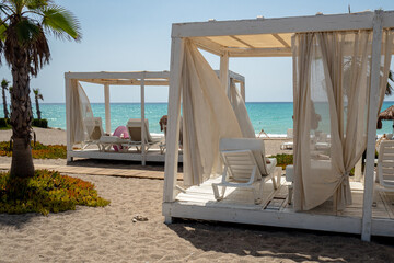 typical tropical atmosphere, beach holiday relax during sunny day in coastal resort with palm trees, baldaquin, deckchairs and ocean in the back, nobody © jan_S