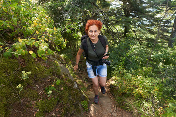Naklejka na ściany i meble Woman hiker with camera on a trail