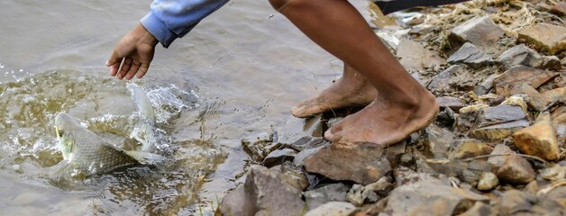 Hombre pescando descalzo a la orilla del rio.