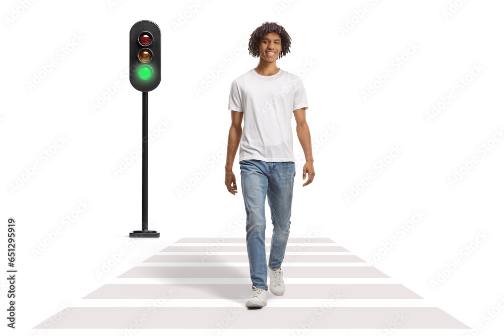 Sticker Full length portrait of an african american guy smiling and walking at pedestrian crossing