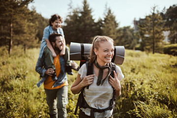 Happy young Caucasian family hiking through the forest in the mountains - obrazy, fototapety, plakaty