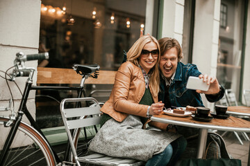 Middle aged Caucasian couple taking a selfie on a smartphone while on a date in a outdoor caf? in the city
