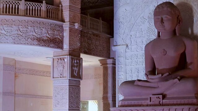 isolated red stone jain god holy statue in meditation from different angle