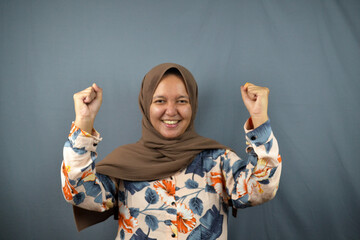portrait of happy excited muslim woman raise her arm while looking at the camera. muslim lifestyle...