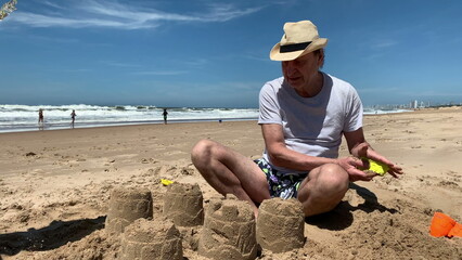 Grandpa with children at beach building sandcastle