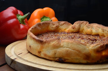 A Pizza like dough with delicious spicy ingredients isolated on a black background.