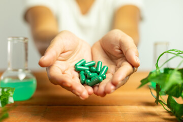 Natural laboratory, hands holding green pills, nature in medicine, herbal capsules, supplements,...