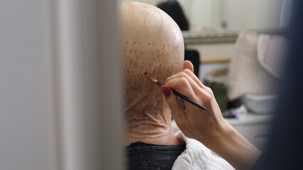 The make-up artist applies make-up to the actor as if he were bald. Make-up artist gives stage...