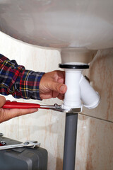 Plumber's hands adjusting sink pipe