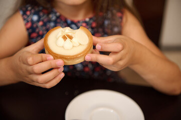 Close up of child hands cupped showing a delicious tartlet with lemon. Confectionery. French bakery. Food concept - obrazy, fototapety, plakaty