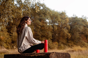 Beautiful young woman sitting alone in the countryside having tea enjoying the silence and beauty...