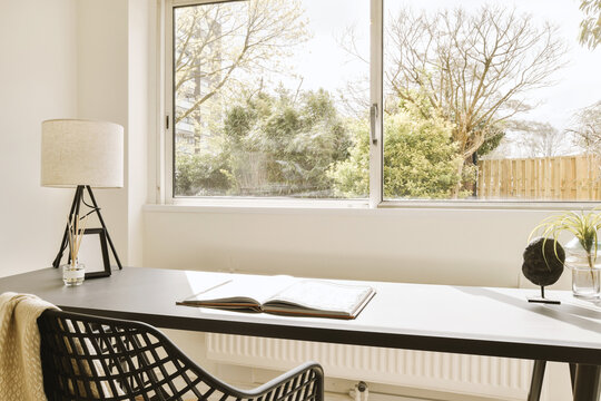 Home office with book and lamp on desk against window