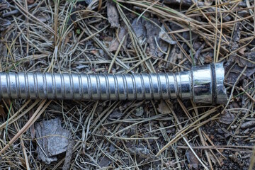 part of one gray metal hose with a nut lies on the ground on the street