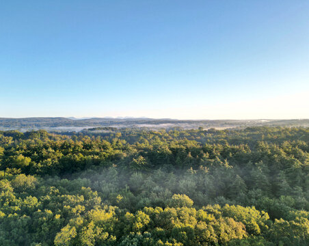 aerial view of distant foggy catskills mountains at sunrise (golden hour, sunset) with fog in the trees on a clear day with blue sky