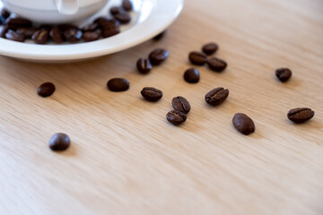 Cup of coffee that full of coffee beans on wooden background with rim light