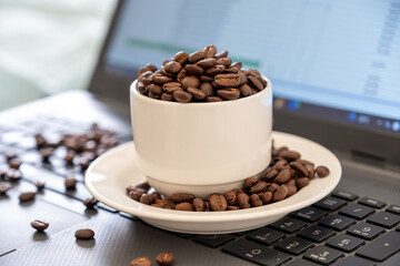 Cup of coffee that full of coffee beans on laptop background with rim light represents working...