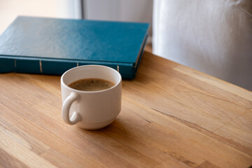 White cup of coffee on wooden background  with book