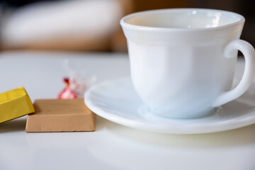 Cup of coffee with pieces of chocloate on white  living room table