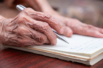 wrinkled hands for elderly person writing notes on his note book