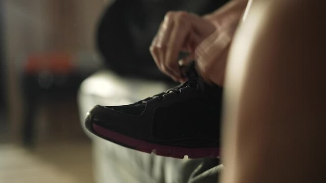 Young Caucasian woman tying her shoes and checking her smartwatch while getting ready to go workout outside