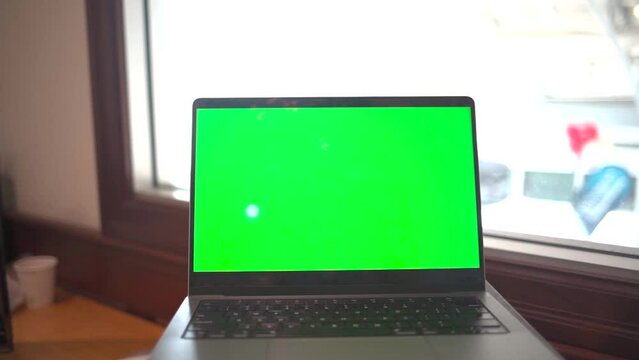 Laptop with green screen in an office.