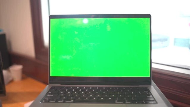 Laptop with green screen in an office.