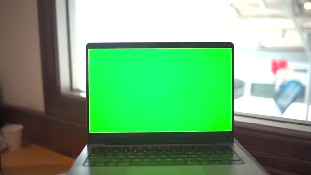 Laptop with green screen in an office.