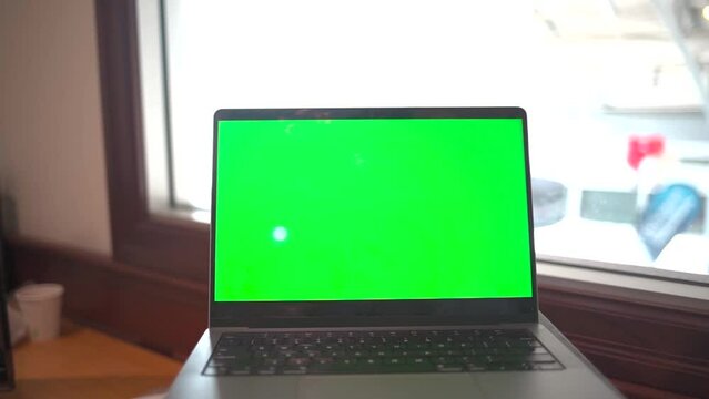 Laptop with green screen in an office.