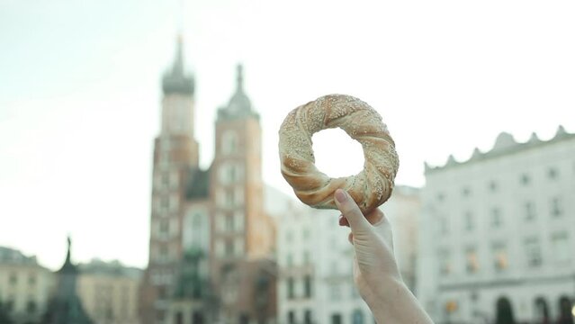 Close up of female tourist holding bagel obwarzanek traditional polish cuisine snack on the market square in Krakow in Poland. Traveling Europe. High quality FullHD footage