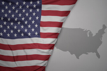 Obraz premium big waving national colorful flag and map of united states of america on the gray background.
