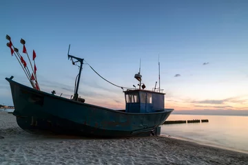 Poster Im Rahmen fishing boat on the beach during sunset © roobcio