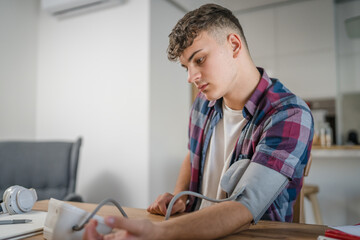 one teenager caucasian man measure check blood pressure at home alone