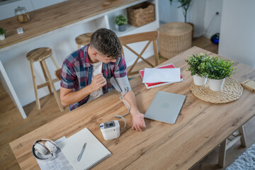 one teenager caucasian man measure check blood pressure at home alone