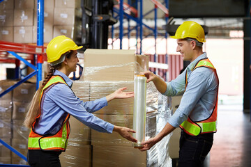 factory workers or warehouser wrapping stretch film parcel on pallet covered cardboard boxed in...