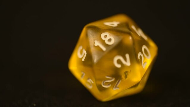 Yellow d20 tabletop board game die rotating tabletop gaming component amber color