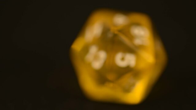 Yellow d20 tabletop board game die rotating tabletop gaming component amber color