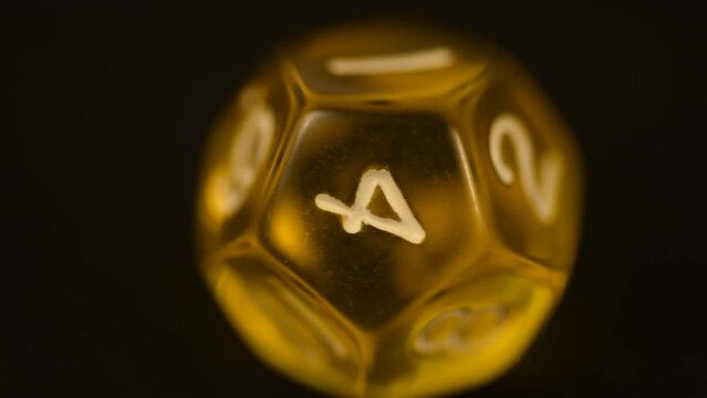 Macro video of Yellow d12 tabletop board game die rotating tabletop gaming component amber color