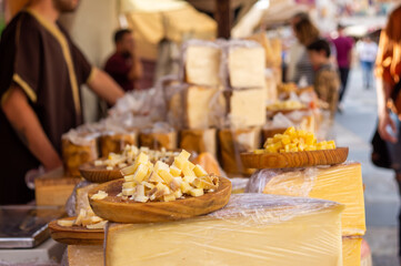 Traditional cheese street stall, with a display of cheeses on a plate in the foreground and the background out of focus.