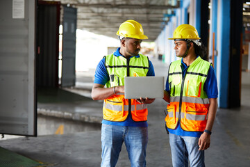 factory workers talking and working on laptop computer in the warehouse storage