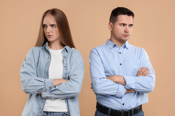 Portrait of resentful couple with crossed arms on beige background