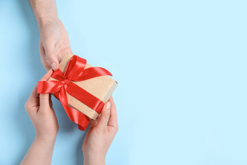 Man giving gift box to woman on light blue background, top view. Space for text