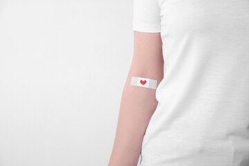 Blood donation concept. Woman with adhesive plaster on arm against white background, closeup. Space...