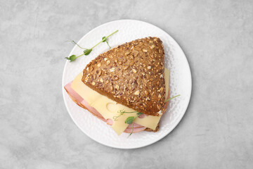 Delicious sandwich with ham and cheese on light gray table, top view