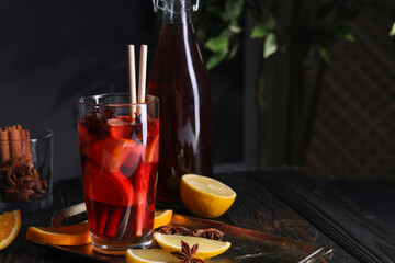 Glass of aromatic punch drink and ingredients on table, space for text